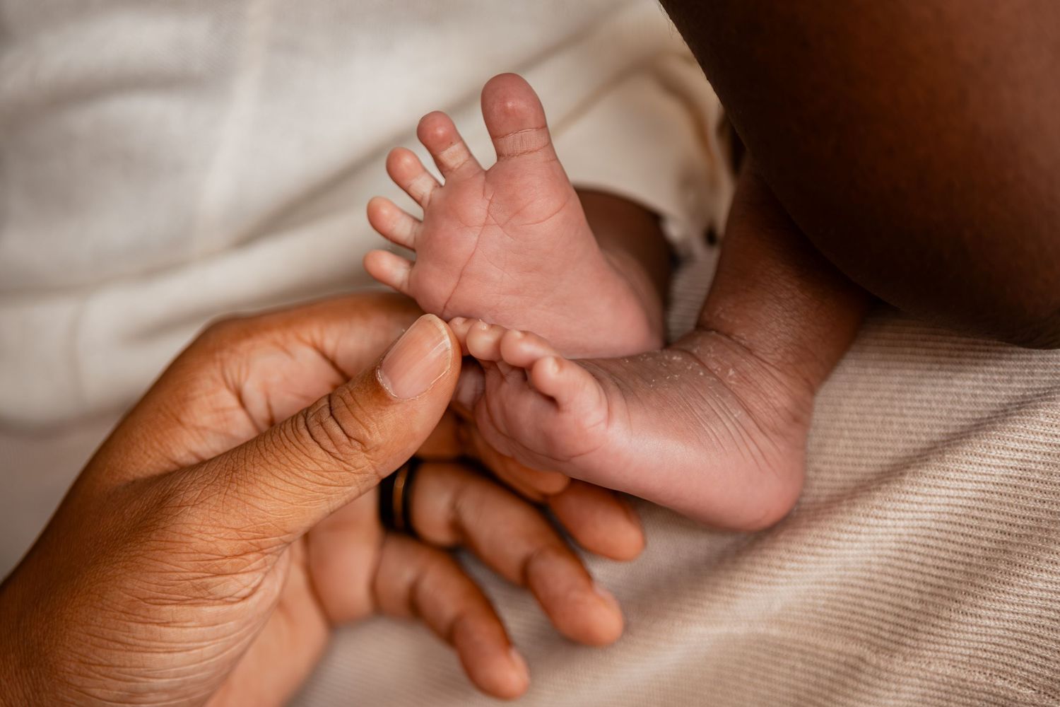 Close-up of a newborn baby's tiny feet resting gently in an adult's caring hands.
