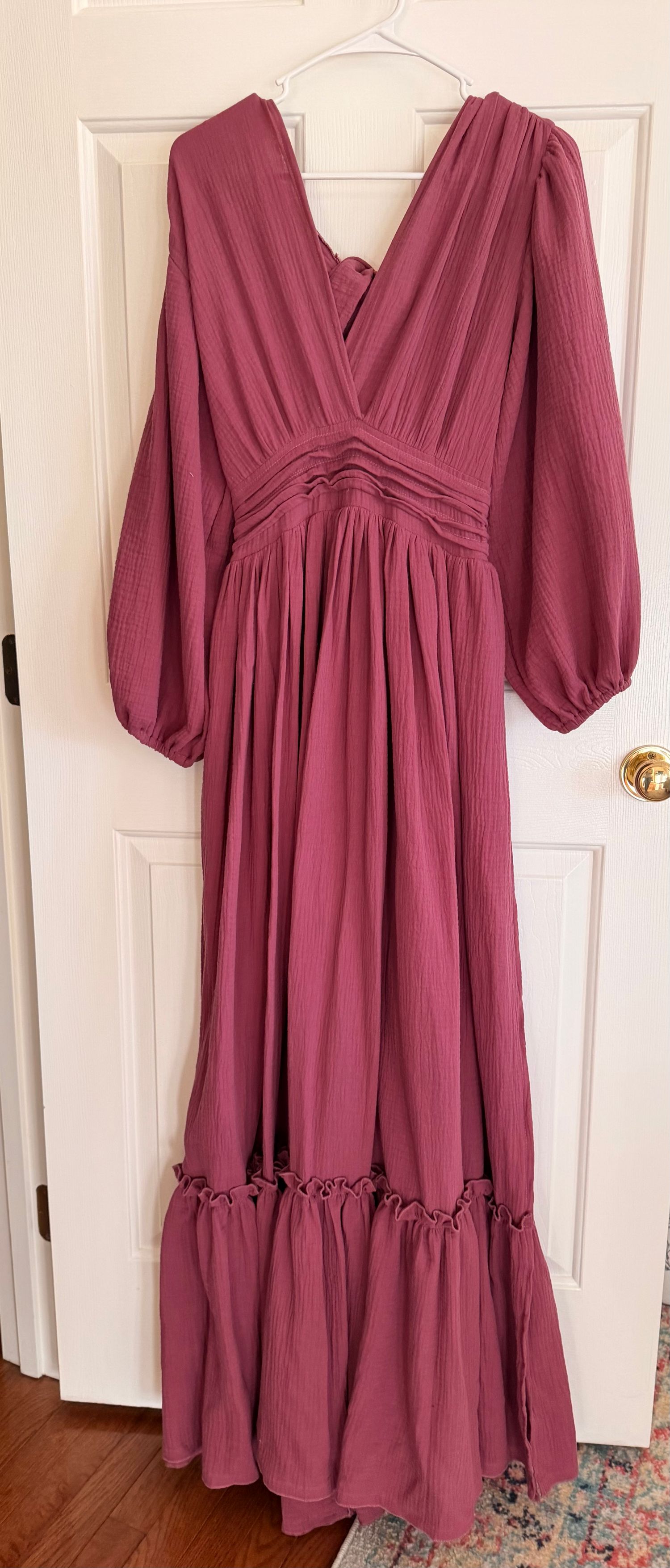 Mauve colored empire waist dress with puff sleeves and tiered ruffle hem displayed on white door.