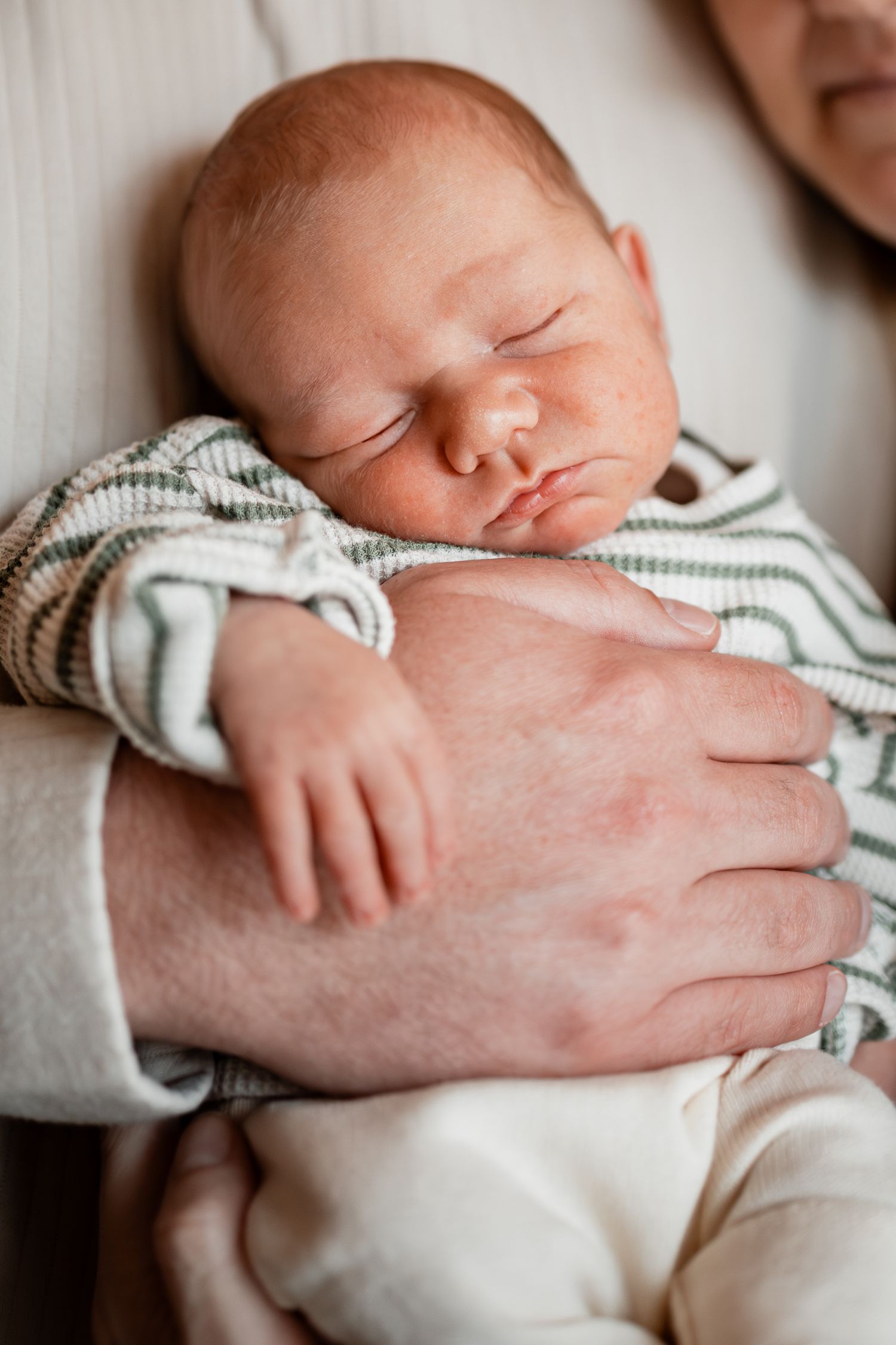 Close-up of sleeping newborn baby in striped onesie.