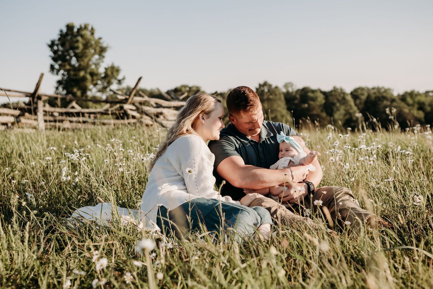 A loving couple enjoying a tender moment together while sitting in a sunlit meadow field.