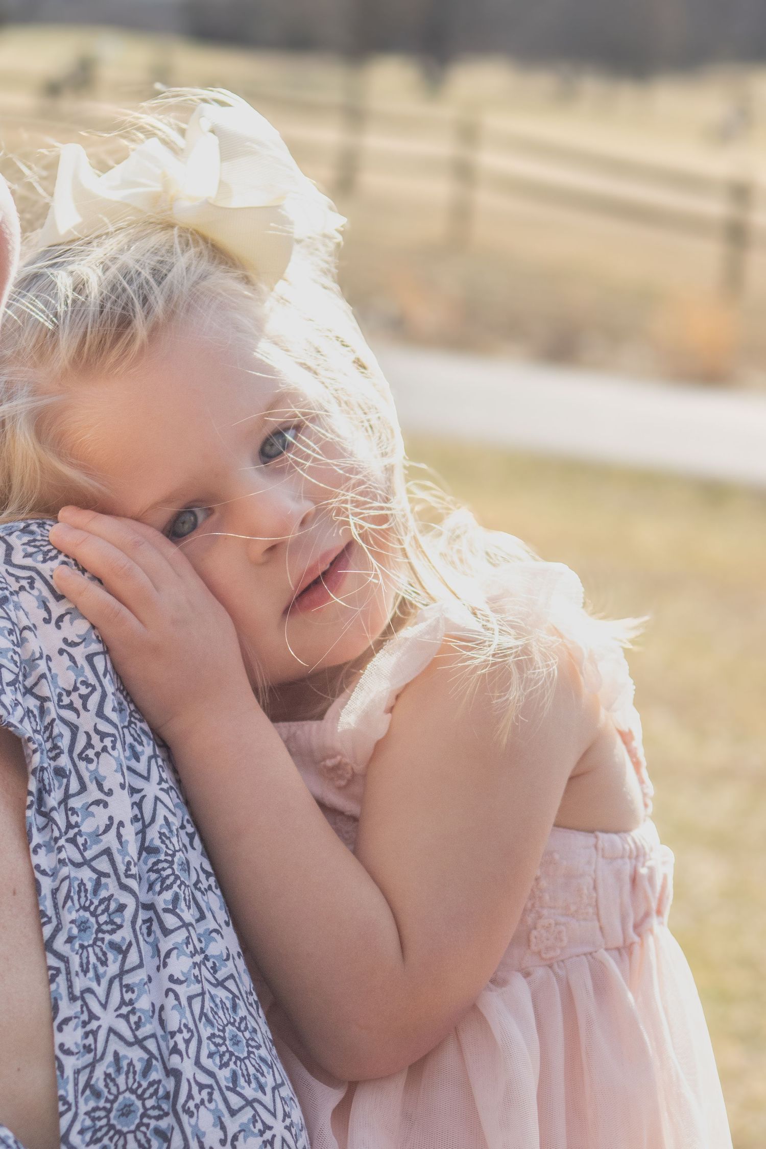 A sweet candid moment showing a child in pink cuddling close outdoors.