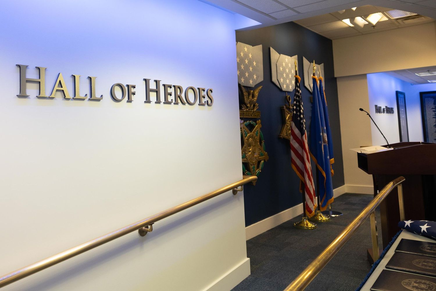 Hall of Heroes display with military medals, American flags, and a podium in a formal government building.