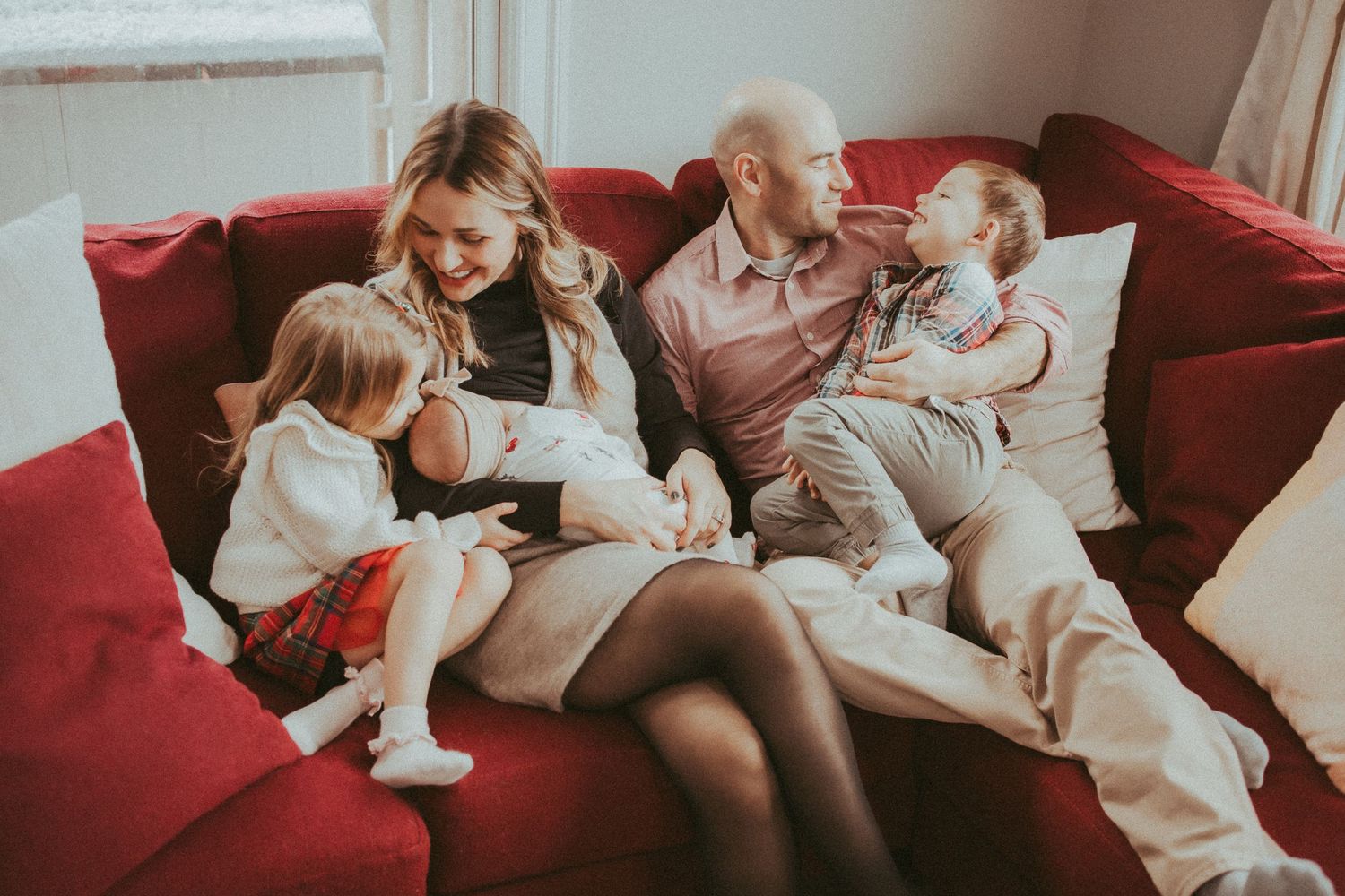 Family members relaxing together on a comfortable red couch while reading and spending quality time at home.