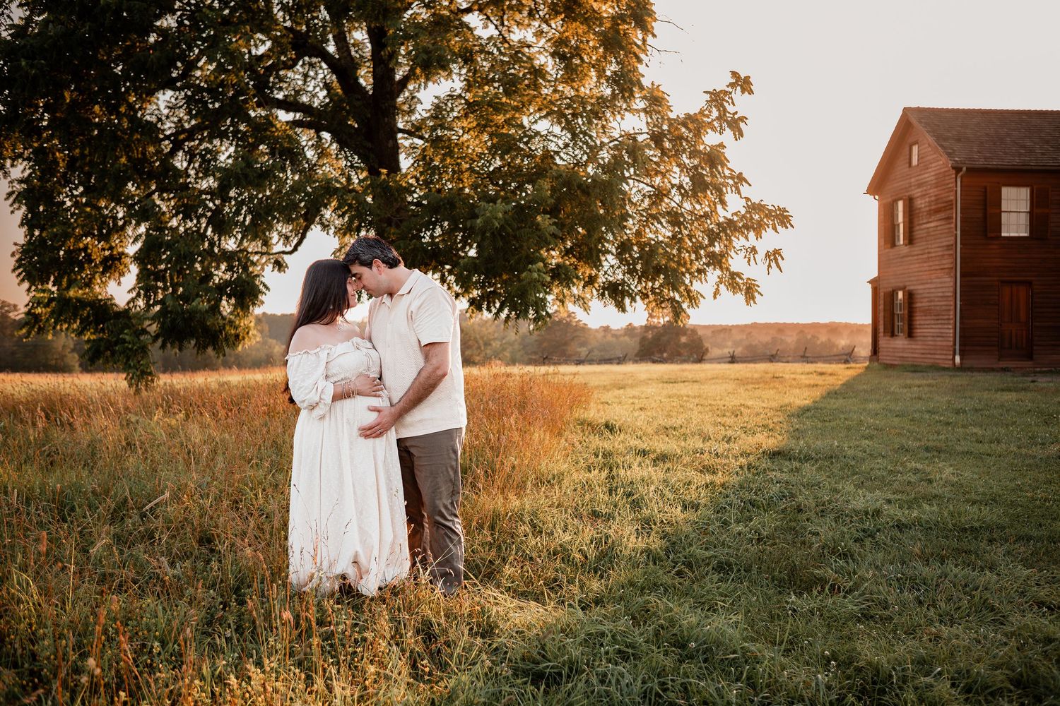A tranquil countryside scene at sunset with a rustic red barn in the background and tall grass swaying in the field.
