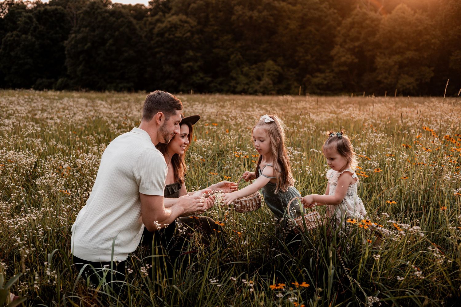 Family shares joyful moments together in a golden sunset meadow during outdoor photo session.
