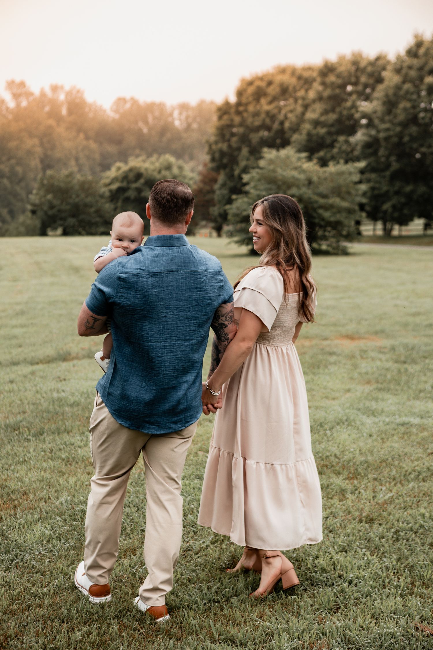 A family walks together through a sunlit park during golden hour, with trees in the background.