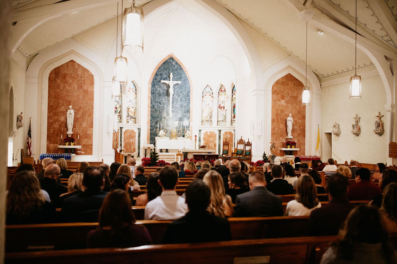 Wide angle view of a church sanctuary filled with guests during a wedding ceremony.