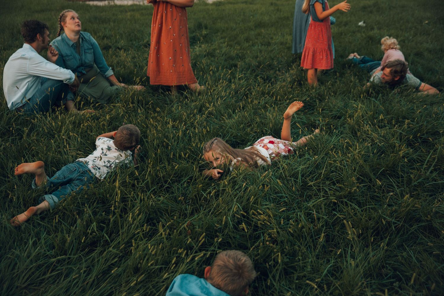 Group enjoying a playful moment while lying in green grass outdoors.
