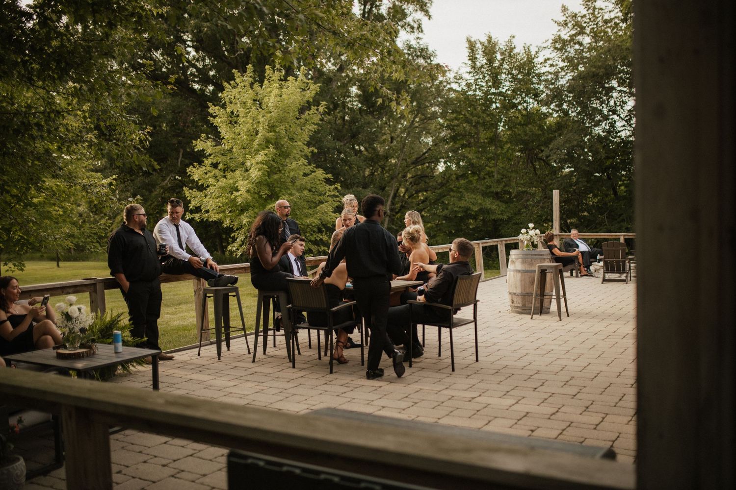 Outdoor wedding venue with stone patio and seating arrangements under trees.