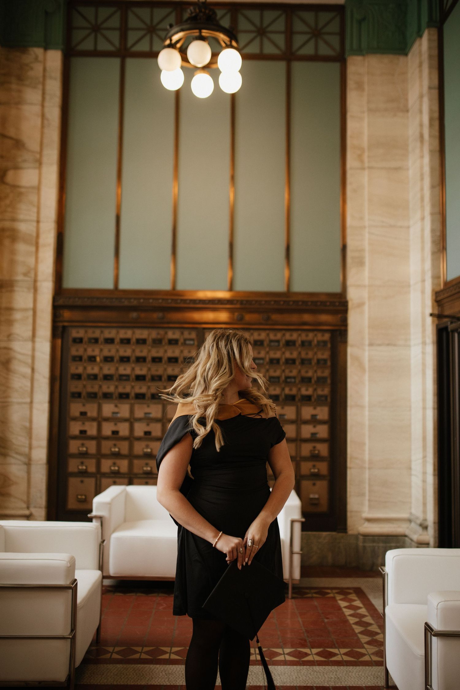 Woman in black dress standing in elegant room with vintage decor.