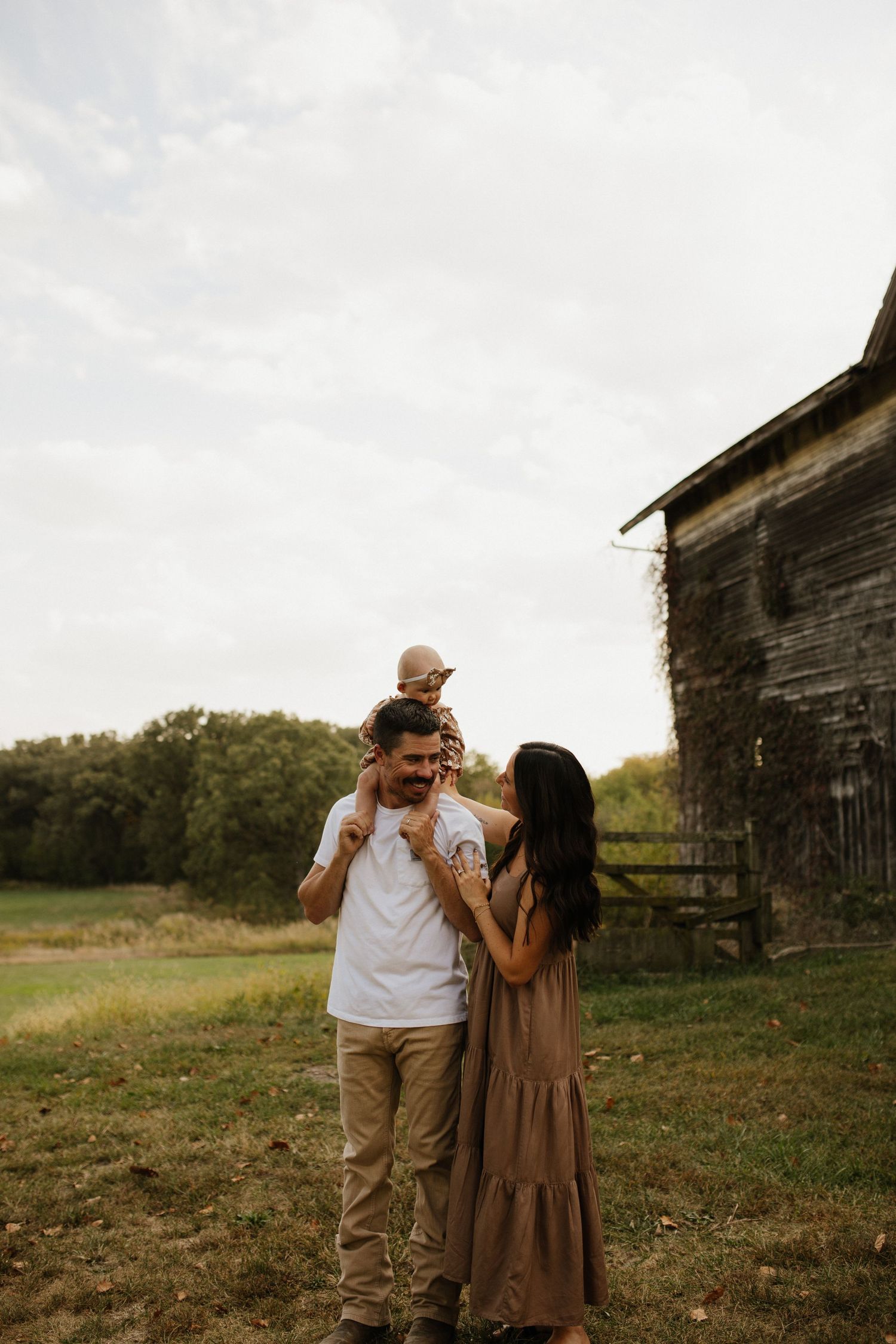 Couple enjoying a romantic moment together in a field with an old barn in the background.
