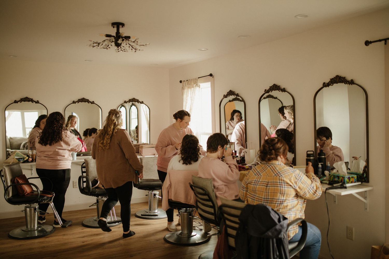 Wedding party getting ready in a vintage-style room with ornate mirrors.