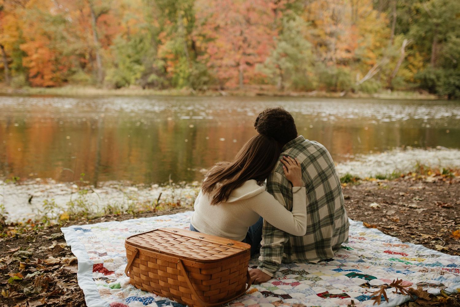 Autumn picnic setup by a lake with blanket and seasonal decorations.