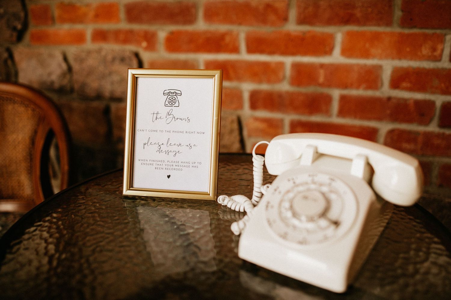 Wedding details displayed on rustic brick wall including framed signs and decor.