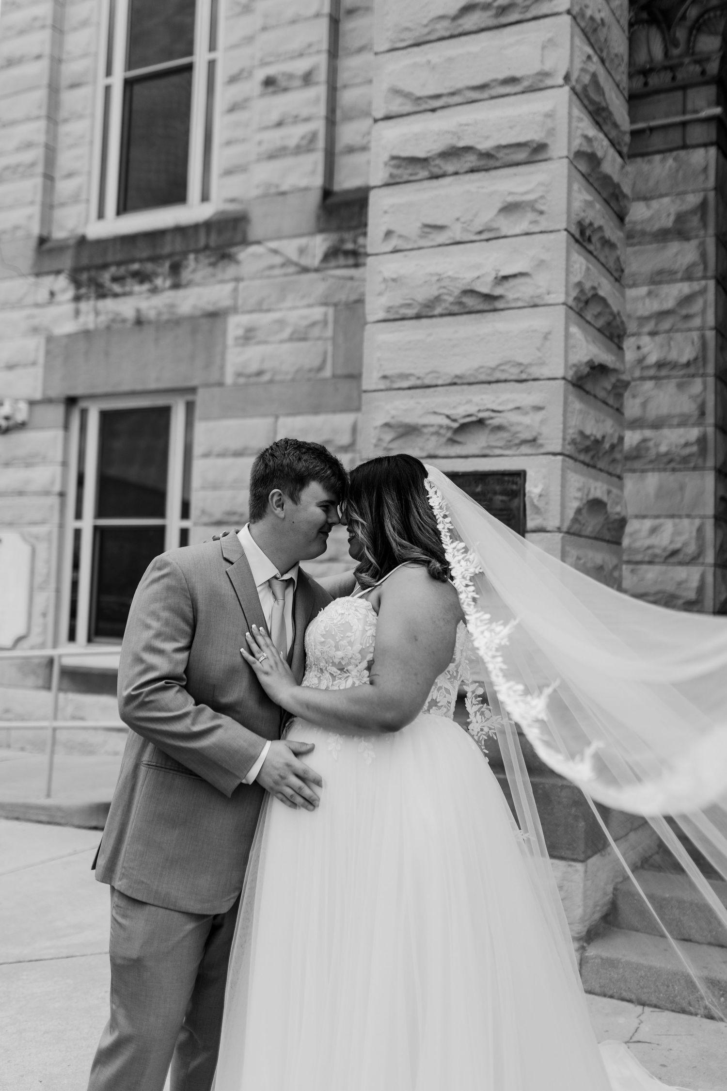Intimate wedding photos of a couple sharing tender moments against a stone wall backdrop.