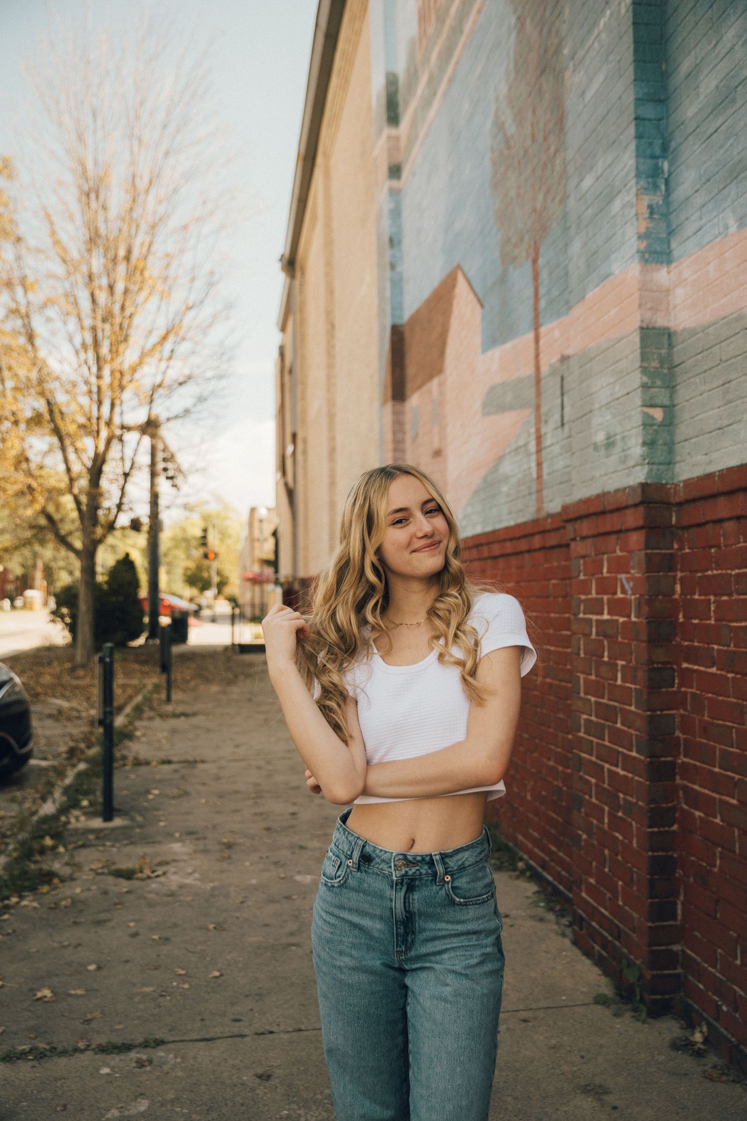 A street style portrait against a painted brick wall on an autumn day.