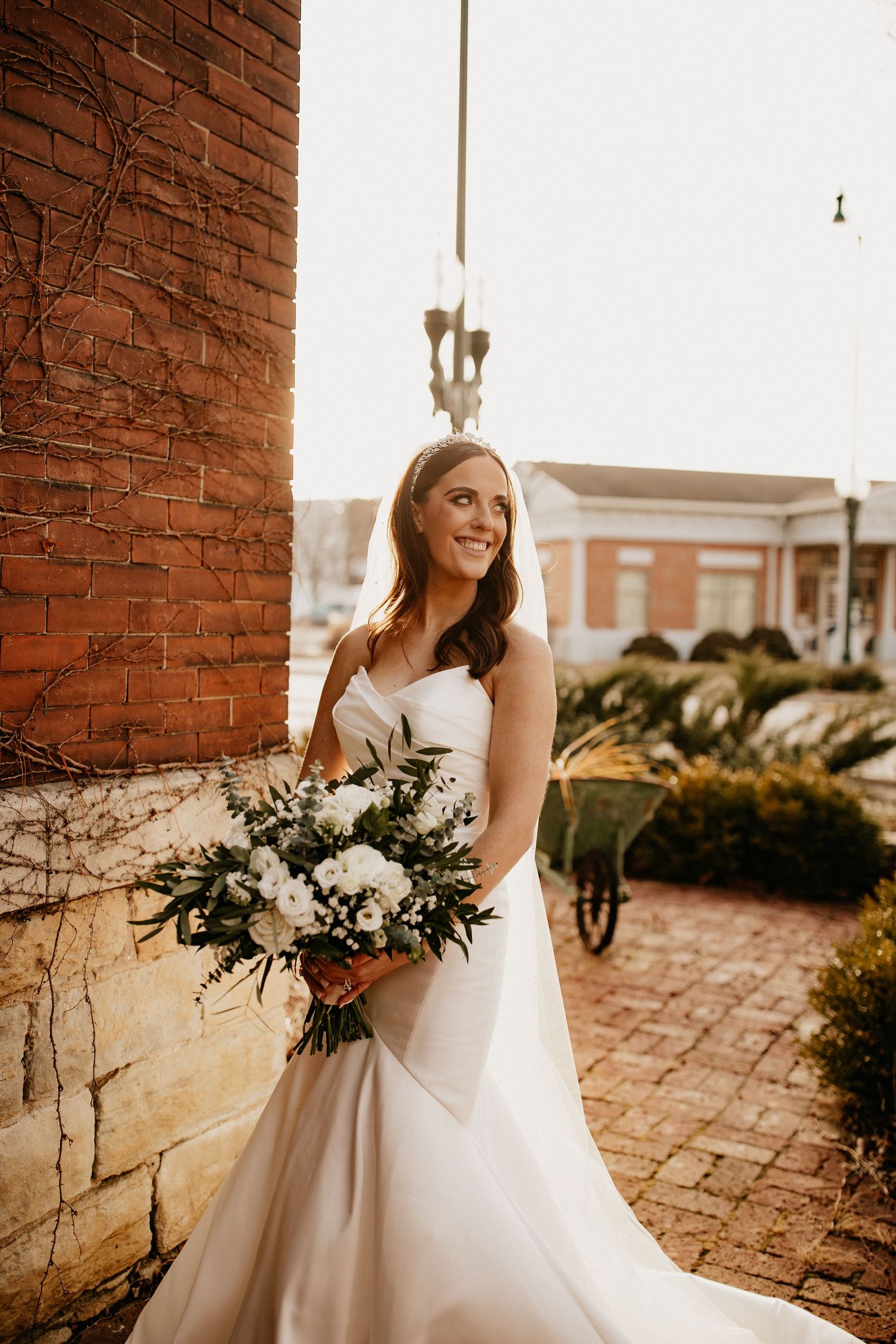 Classic bridal portrait against rustic brick wall with white floral bouquet.