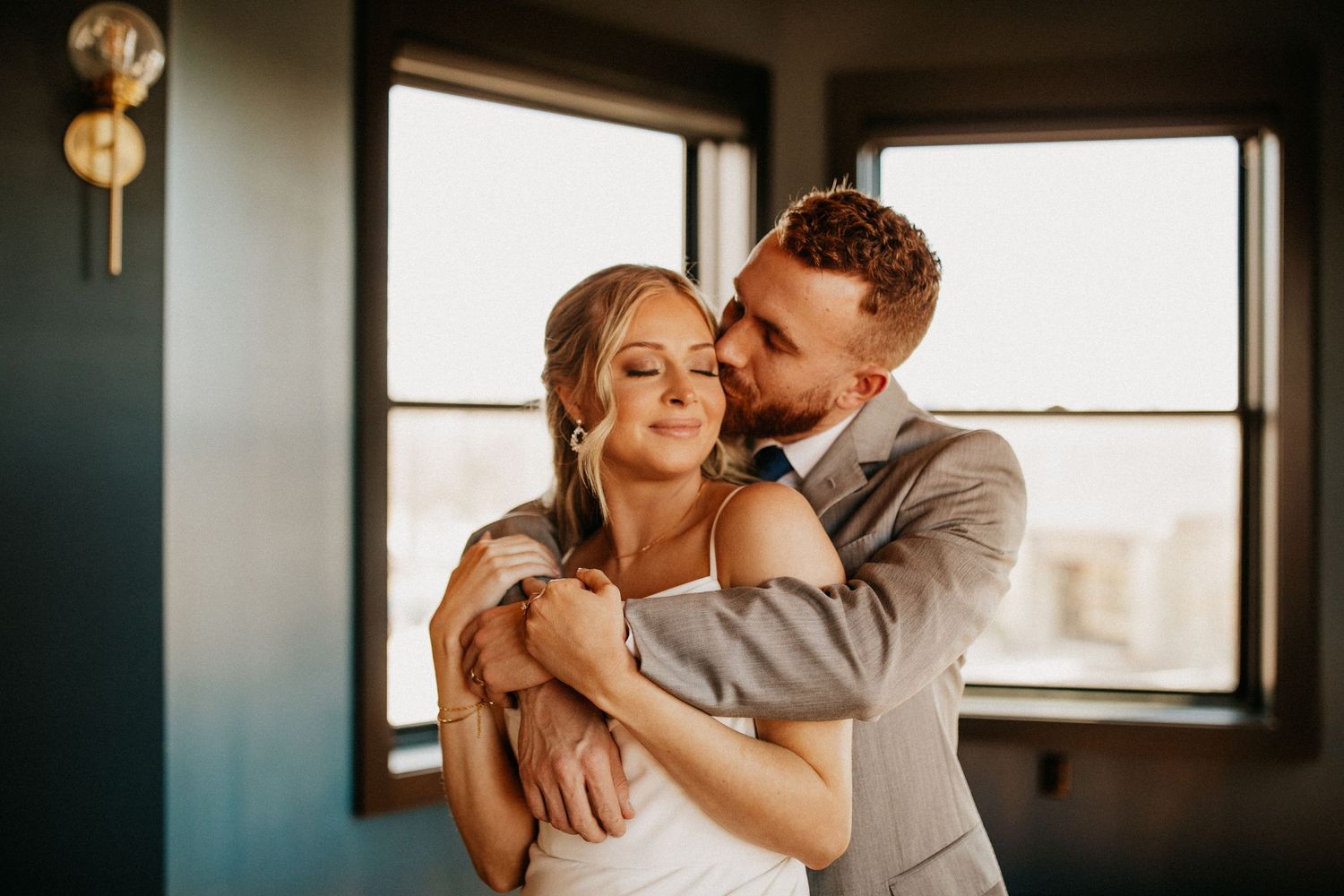 An intimate wedding portrait showing a tender embrace in warm natural light.