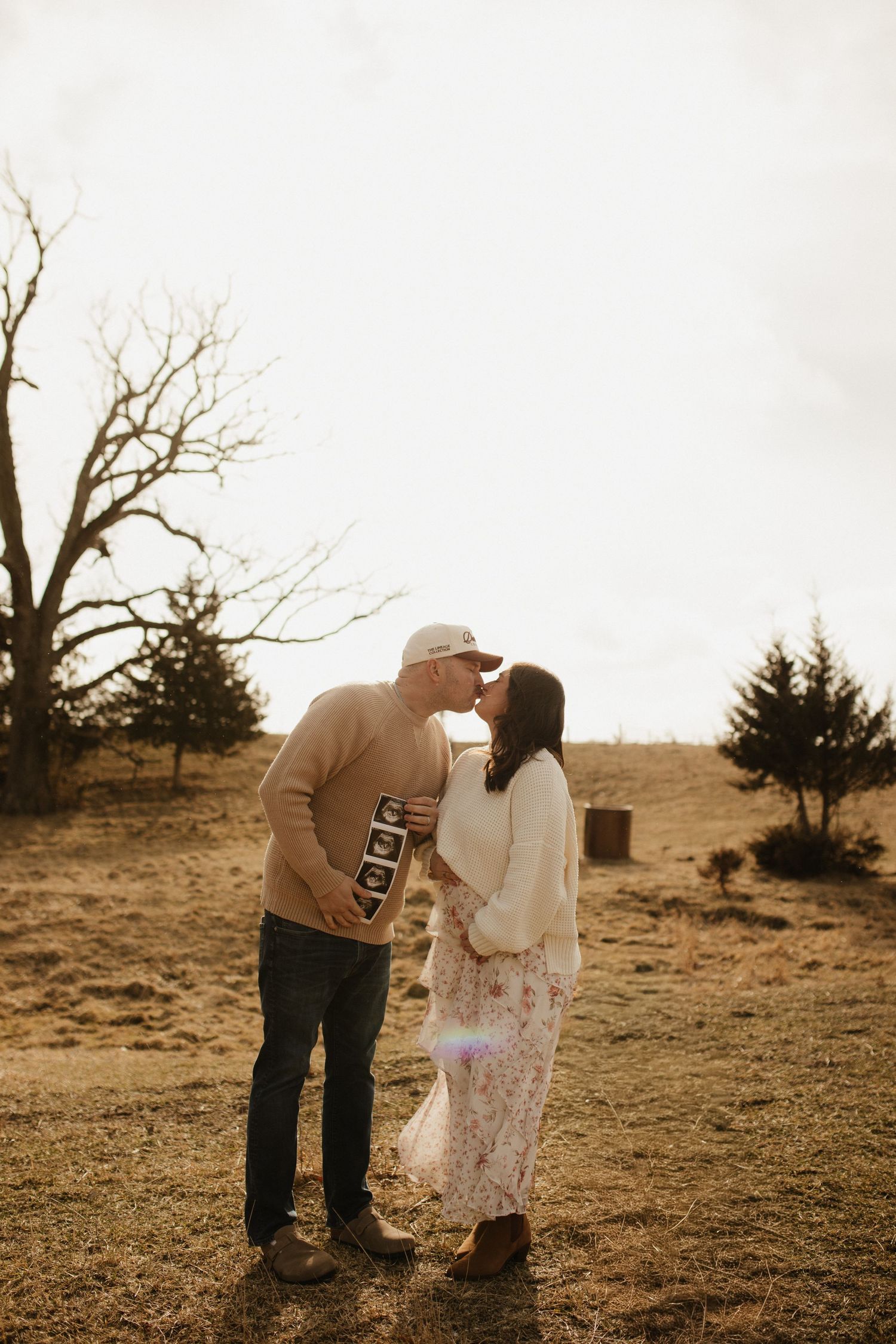 A couple shares a tender moment on a hillside in sepia tones.