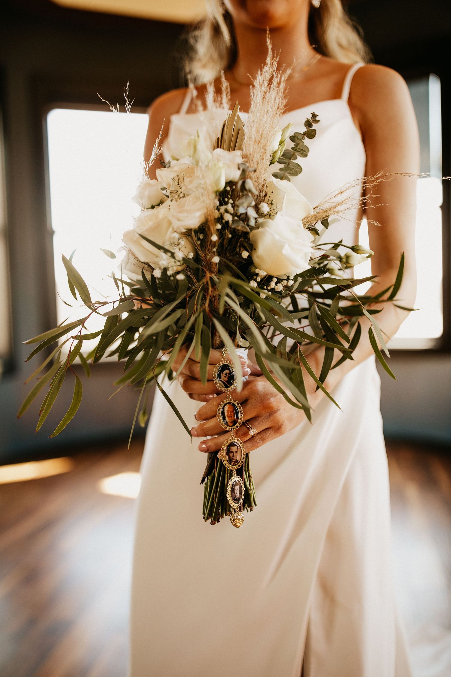 An elegant bridal bouquet with white flowers, pampas grass, and greenery against natural light.
