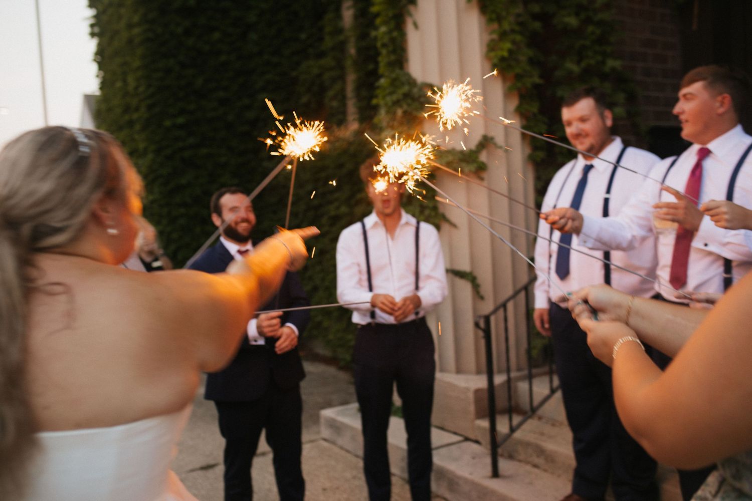 Wedding guests holding sparklers creating a magical nighttime celebration atmosphere.