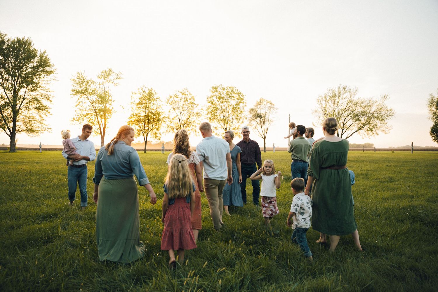 People gathered on a hilltop silhouetted against a golden evening sky.