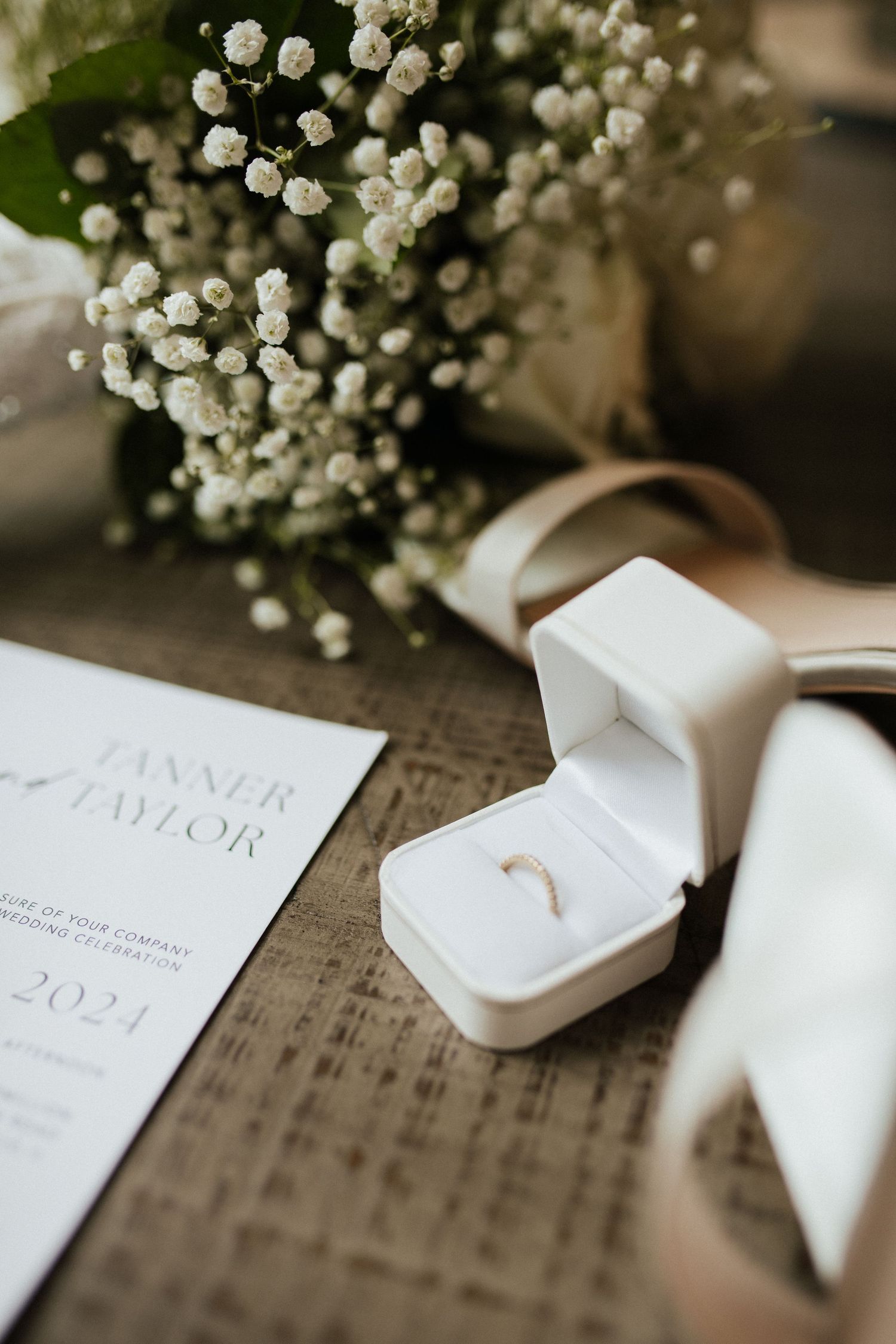 Wedding stationery and delicate baby's breath flowers arranged on a rustic wooden surface.