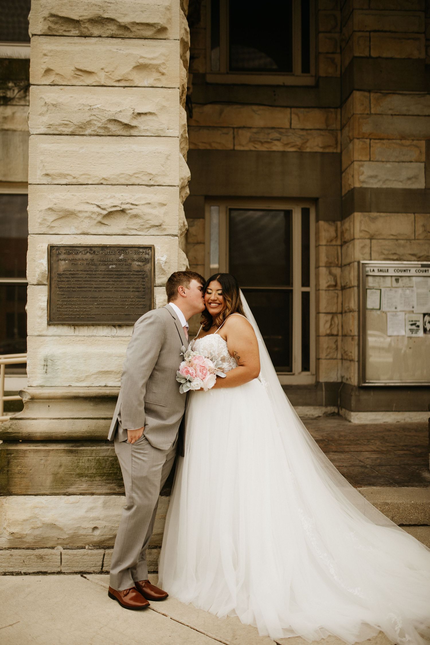 A romantic wedding sequence showing a couple in a white dress and gray suit embracing against a stone building.