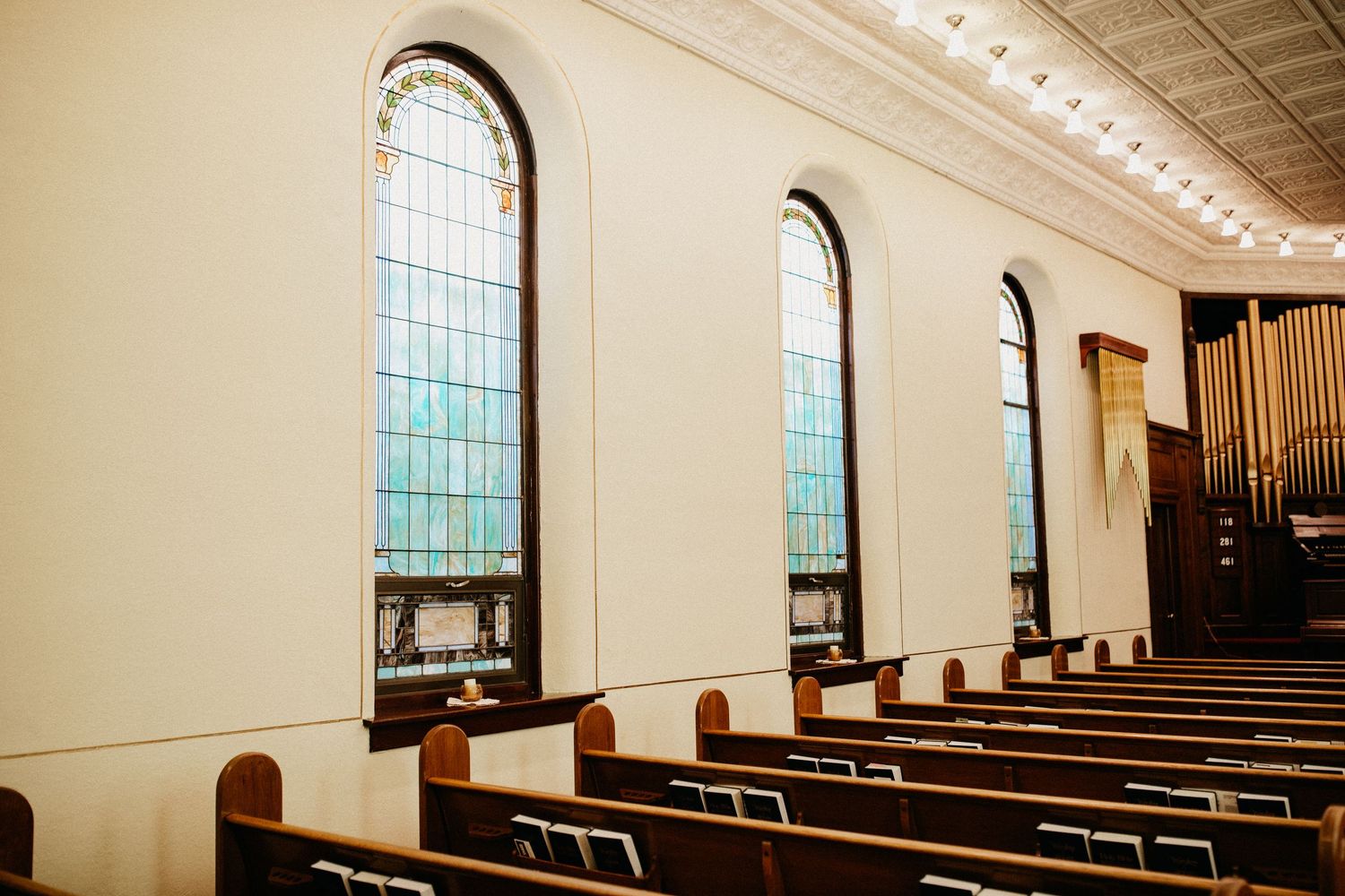 Interior of a church sanctuary with arched windows and wooden pews.