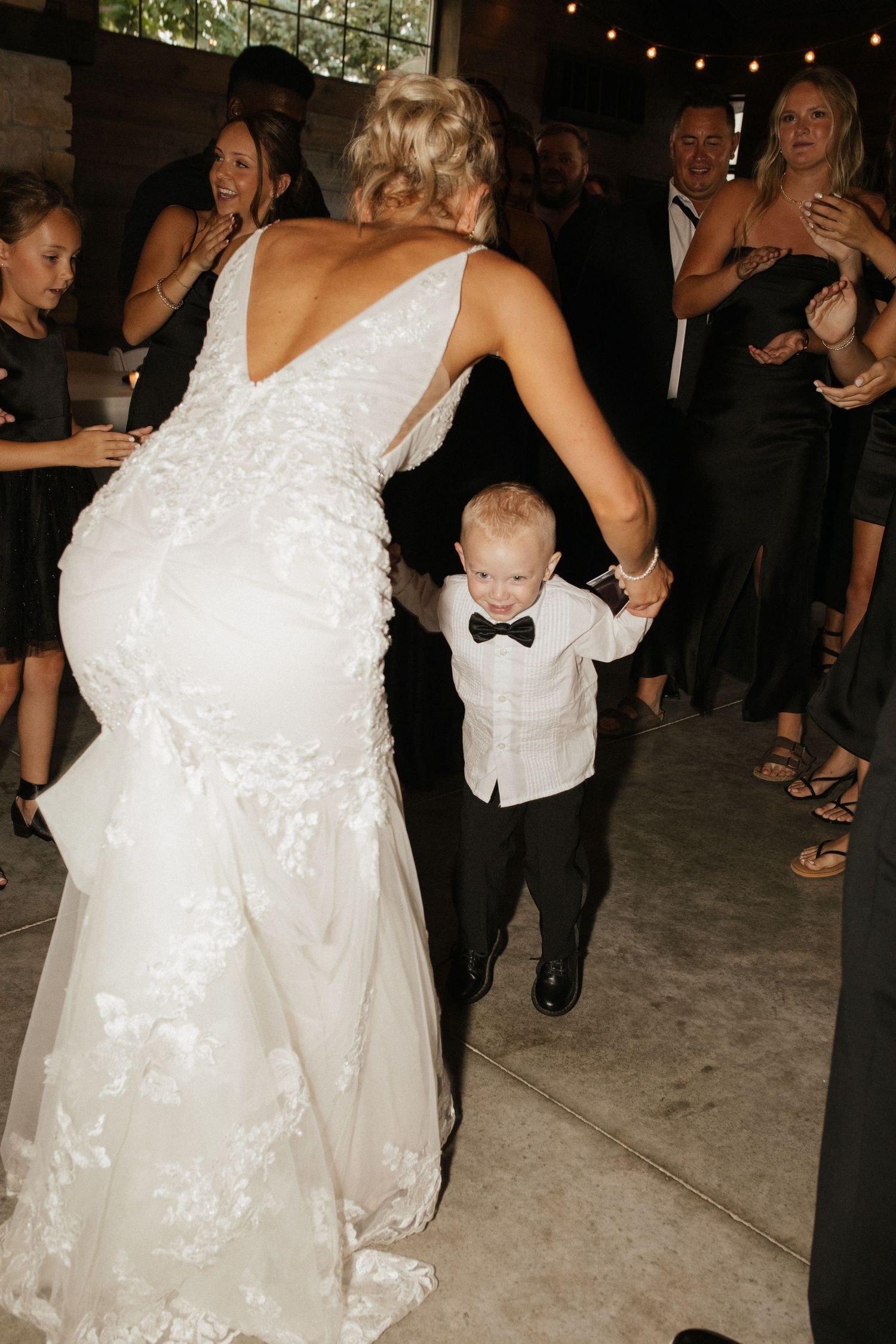 Wedding reception dance floor with guests celebrating in dimly lit venue.