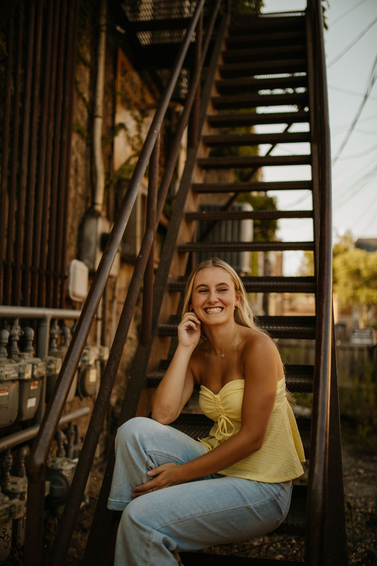 Figure lounges on metal stairs during sunset photo session.