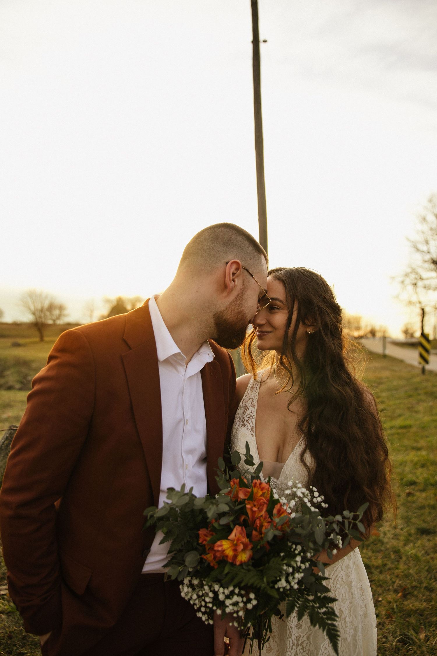 Intimate wedding portrait with autumn-colored bouquet during golden hour.