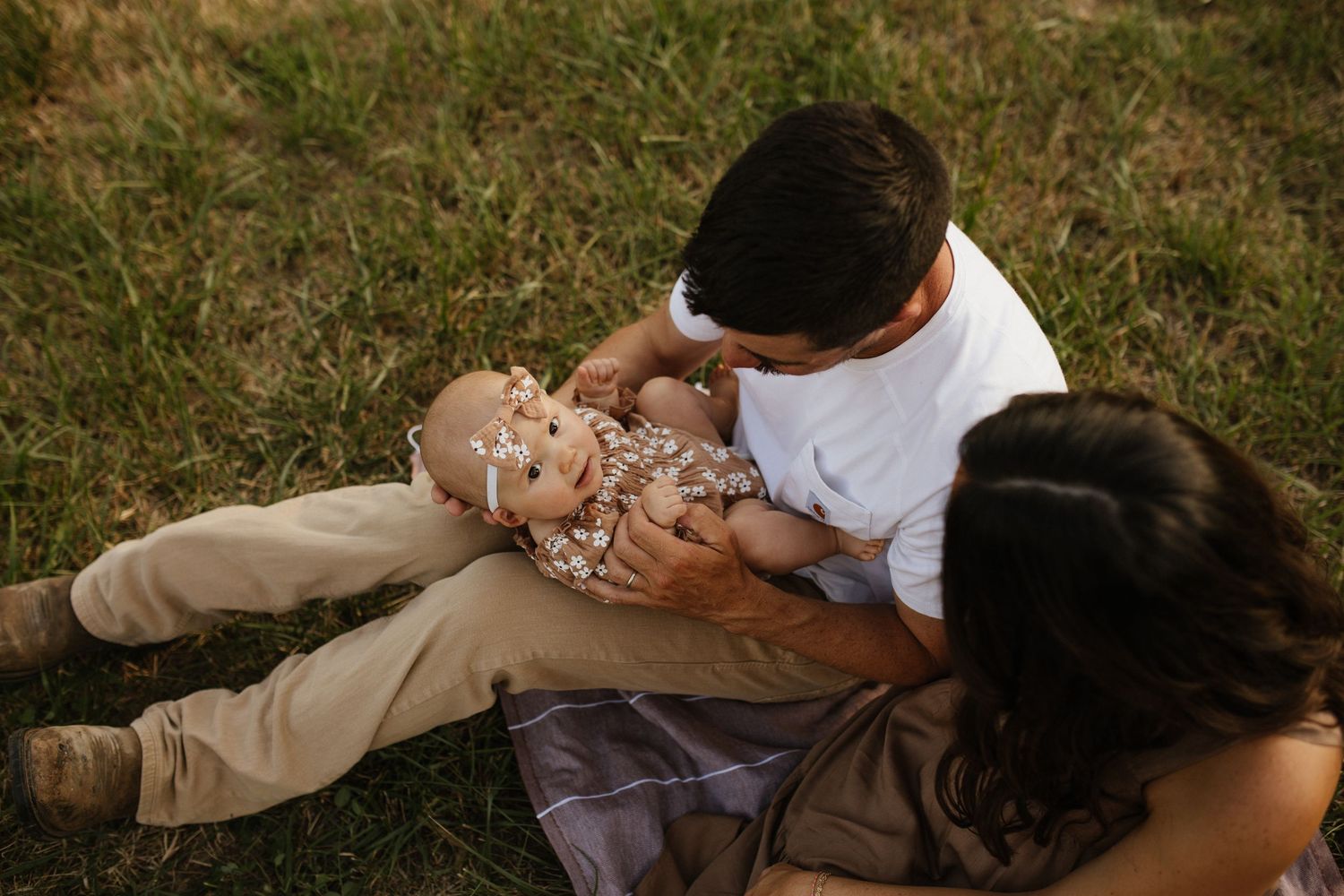 Candid shots of a couple lying in grass during a romantic outdoor photoshoot.