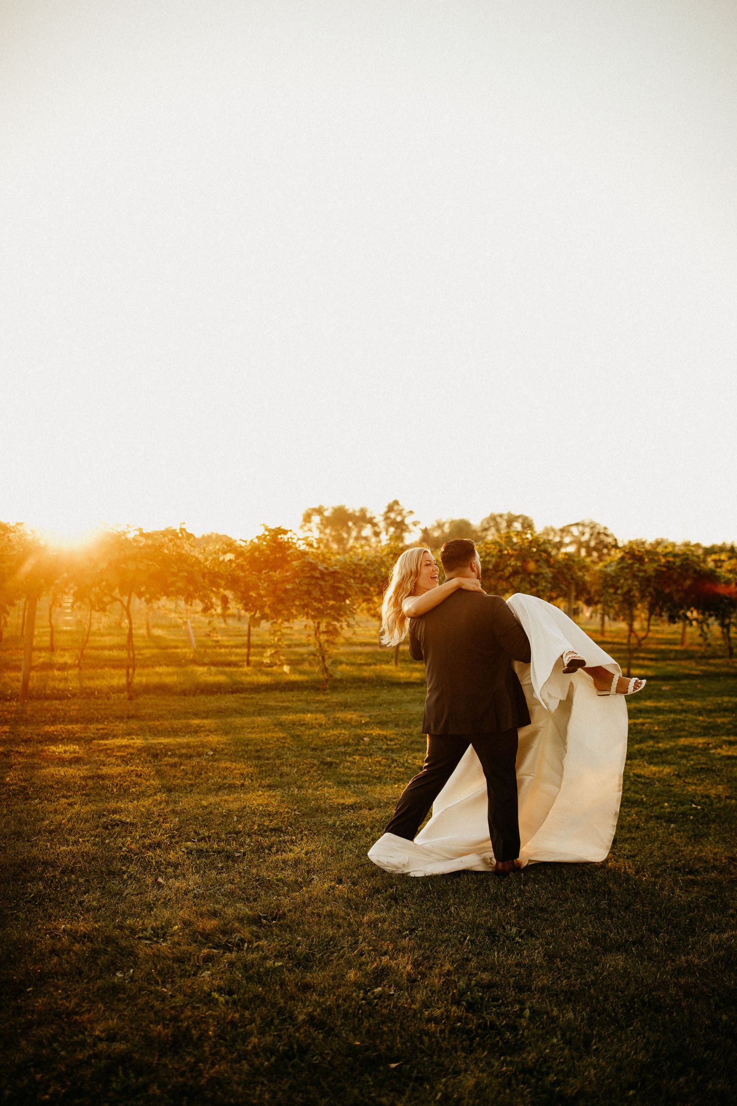 Couple dances in an open field at sunset with dramatic lighting.