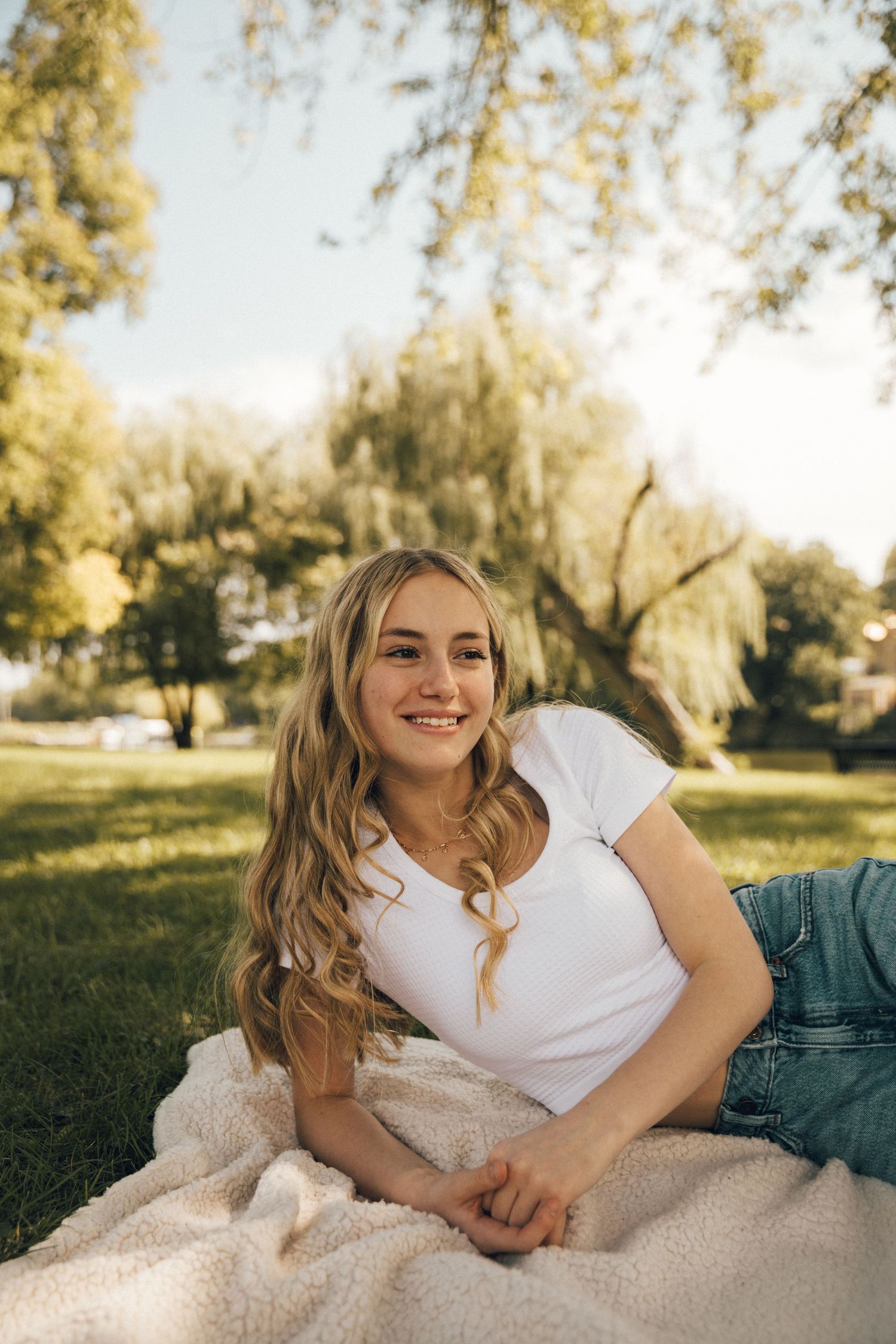A sunny outdoor portrait on a blanket with trees in the background.