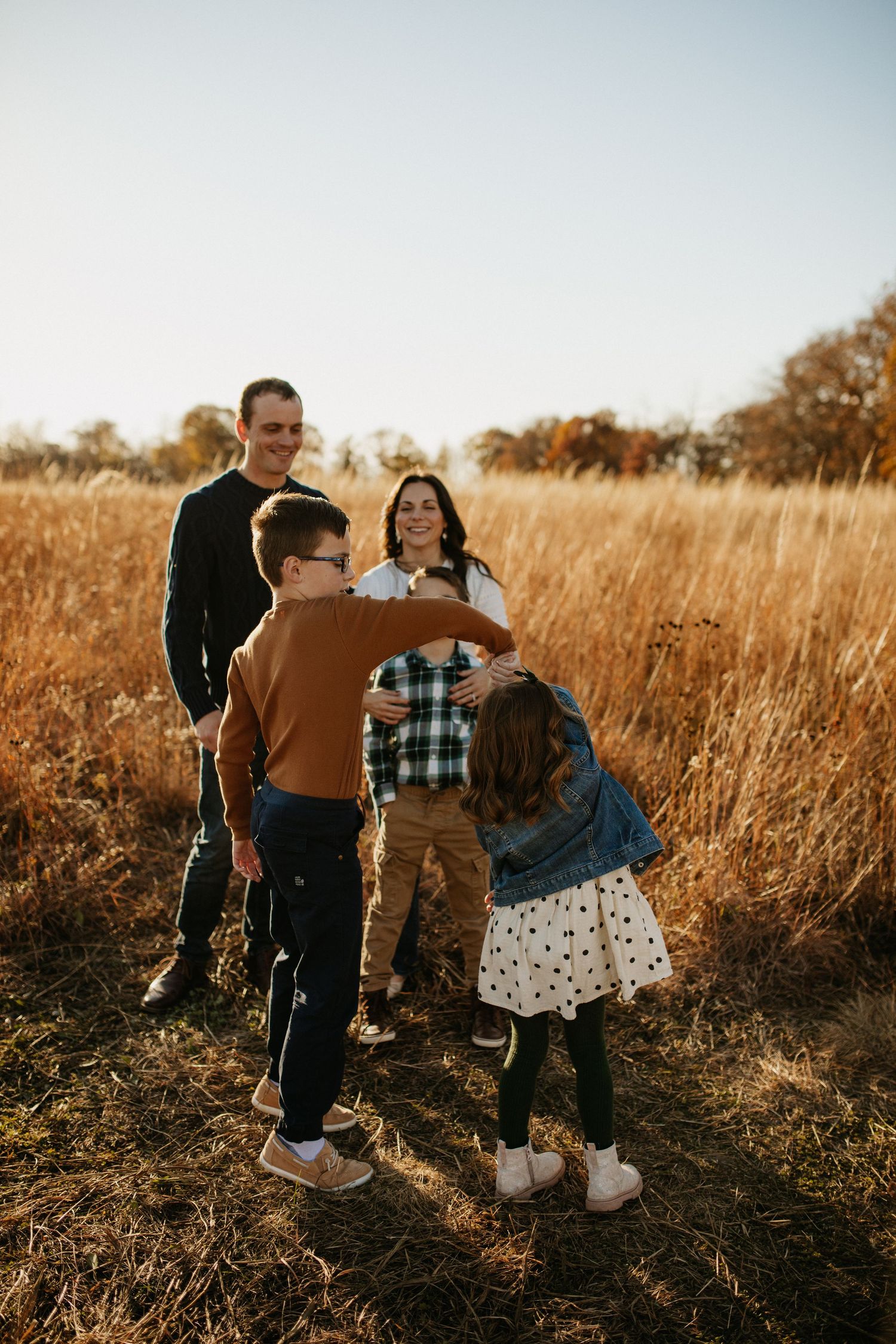 People interacting playfully in a golden field during sunset.
