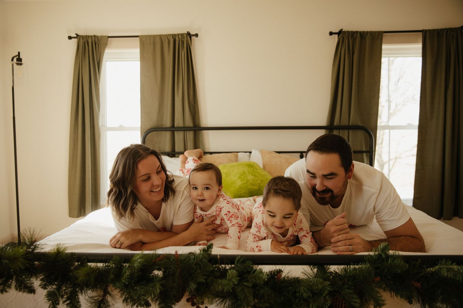 Sweet candid moments of family bonding time on a large bed with natural lighting.