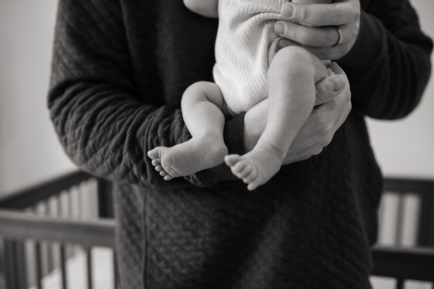 Black and white image of tiny newborn feet being held.