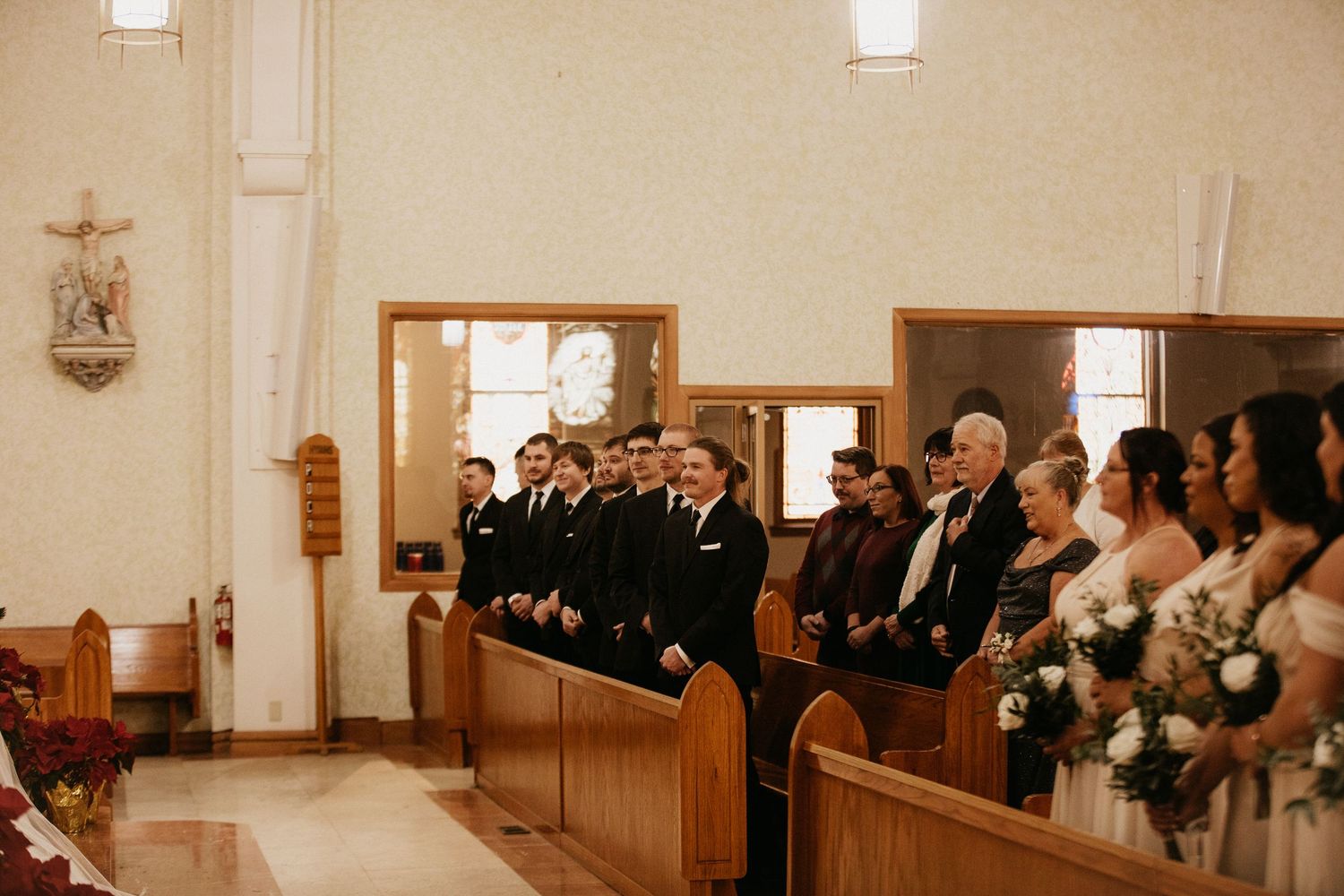 Wedding guests and groomsmen gathered in church pews during a ceremony.