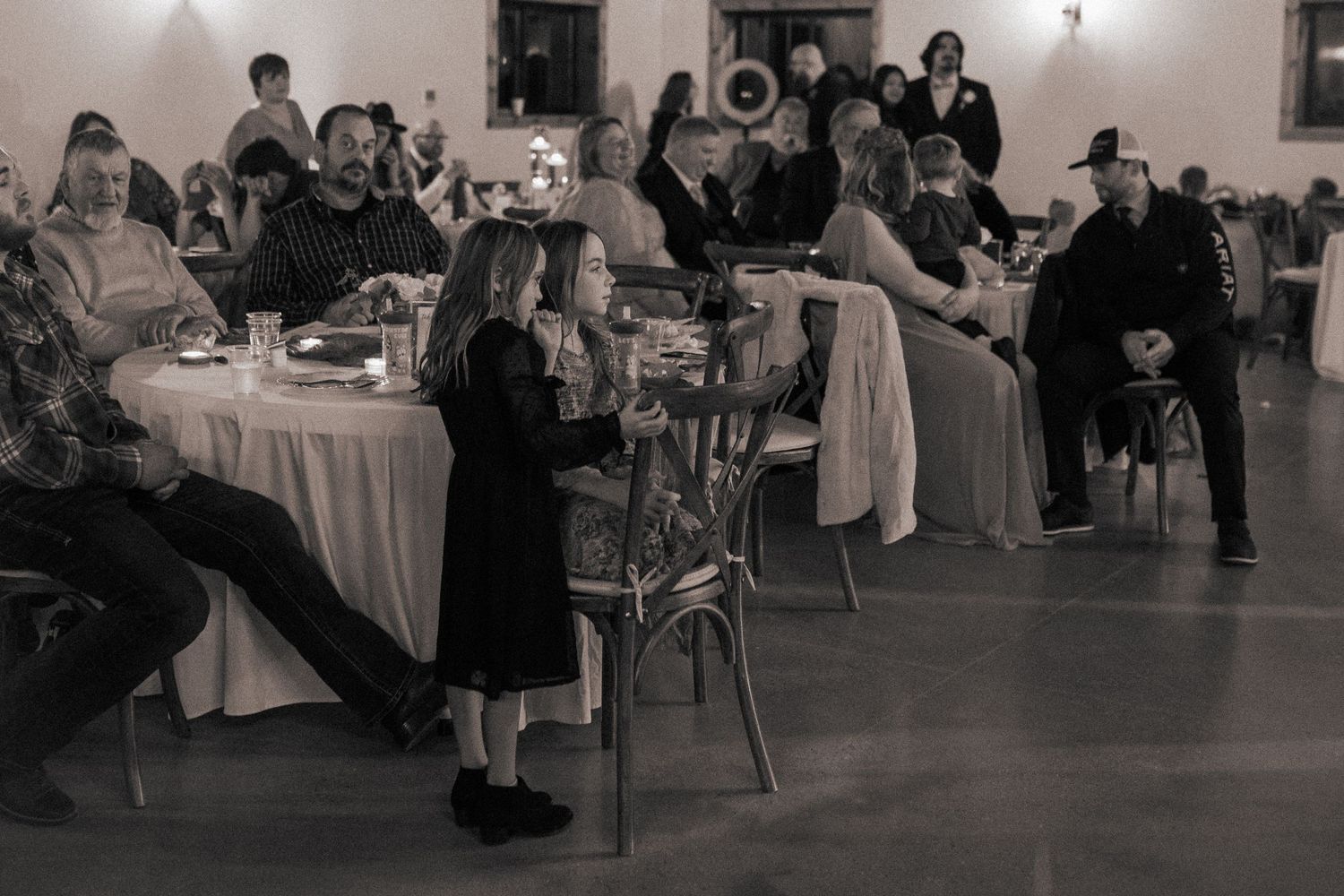 Guests mingle and dine at elegant reception tables in a dimly lit banquet hall.