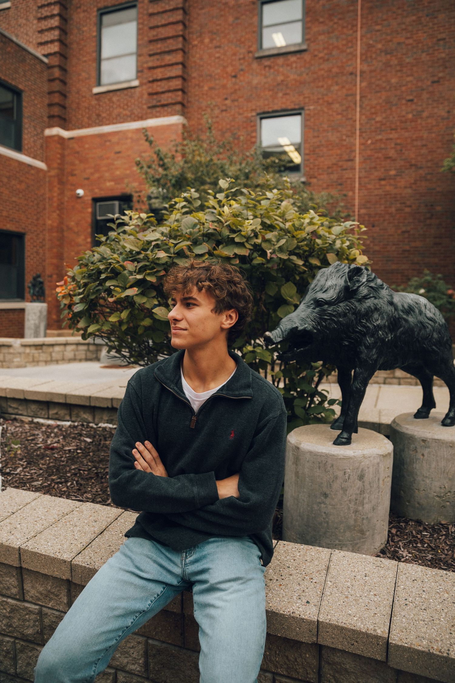 A casual portrait against a brick building with a decorative wolf statue in the background.