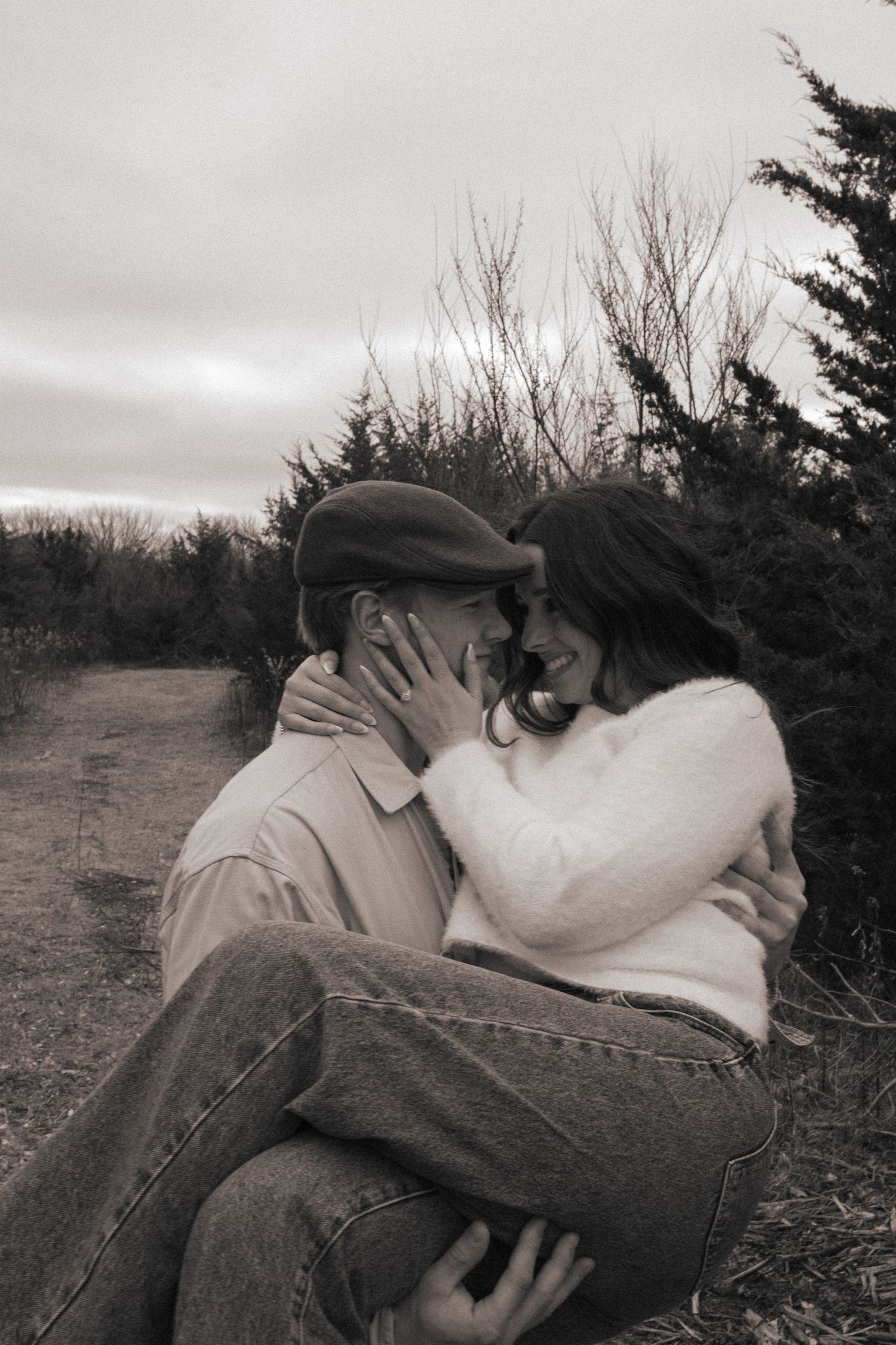 Intimate winter portrait of a couple embracing on a cloudy nature trail.