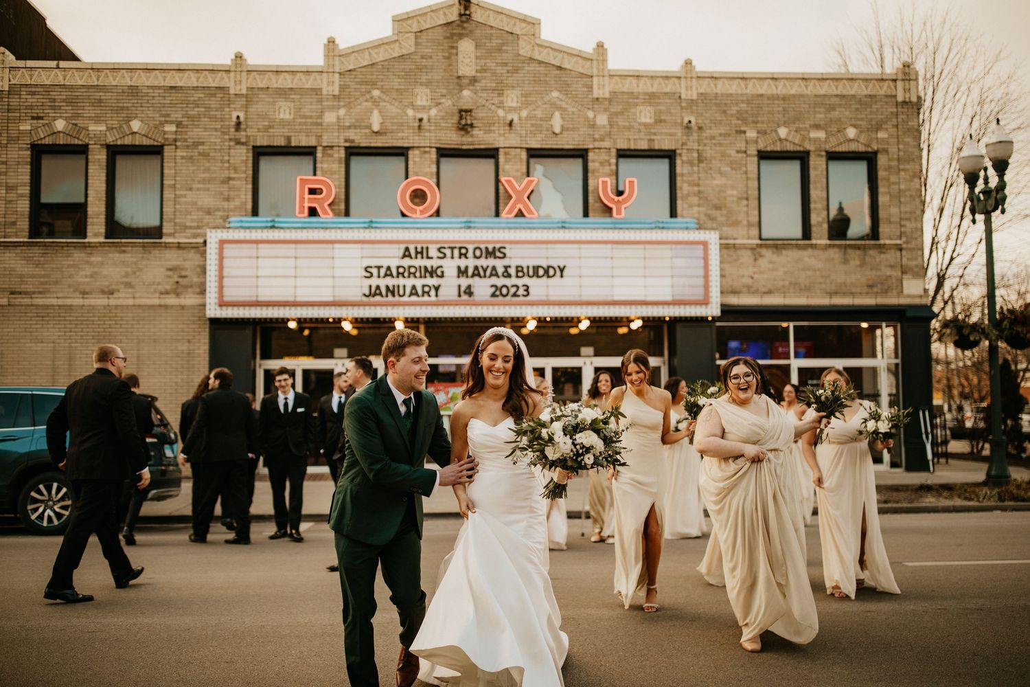 Wedding party walking outside a historic brick building with white columns and arched windows.
