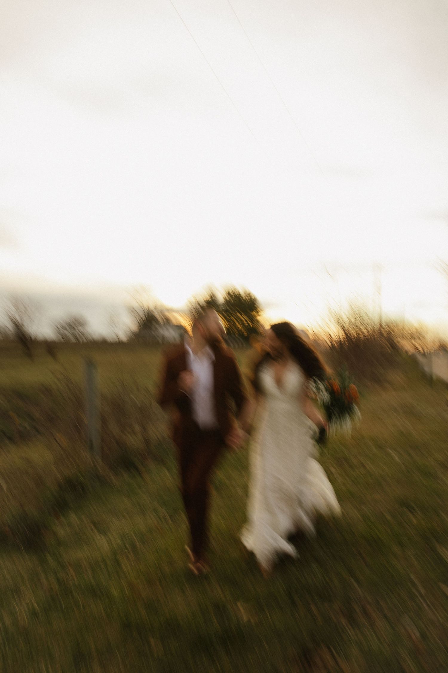 Blurred motion shot of people walking through a golden field at dusk.
