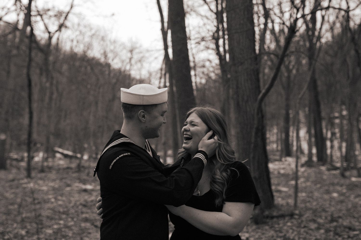 A couple shares an intimate moment in a wooded setting during autumn.