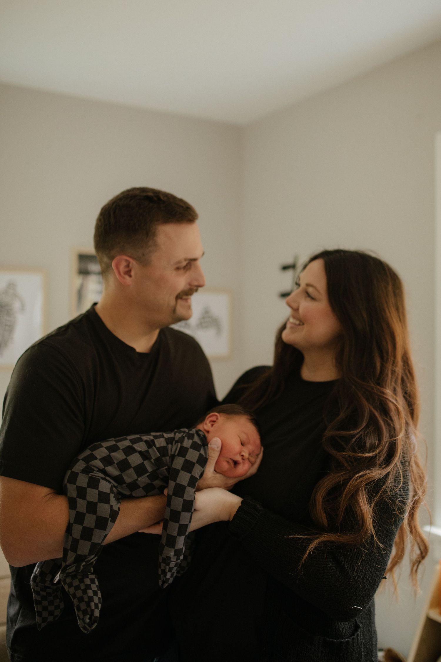Parents sharing loving moments with their newborn in a naturally lit room.