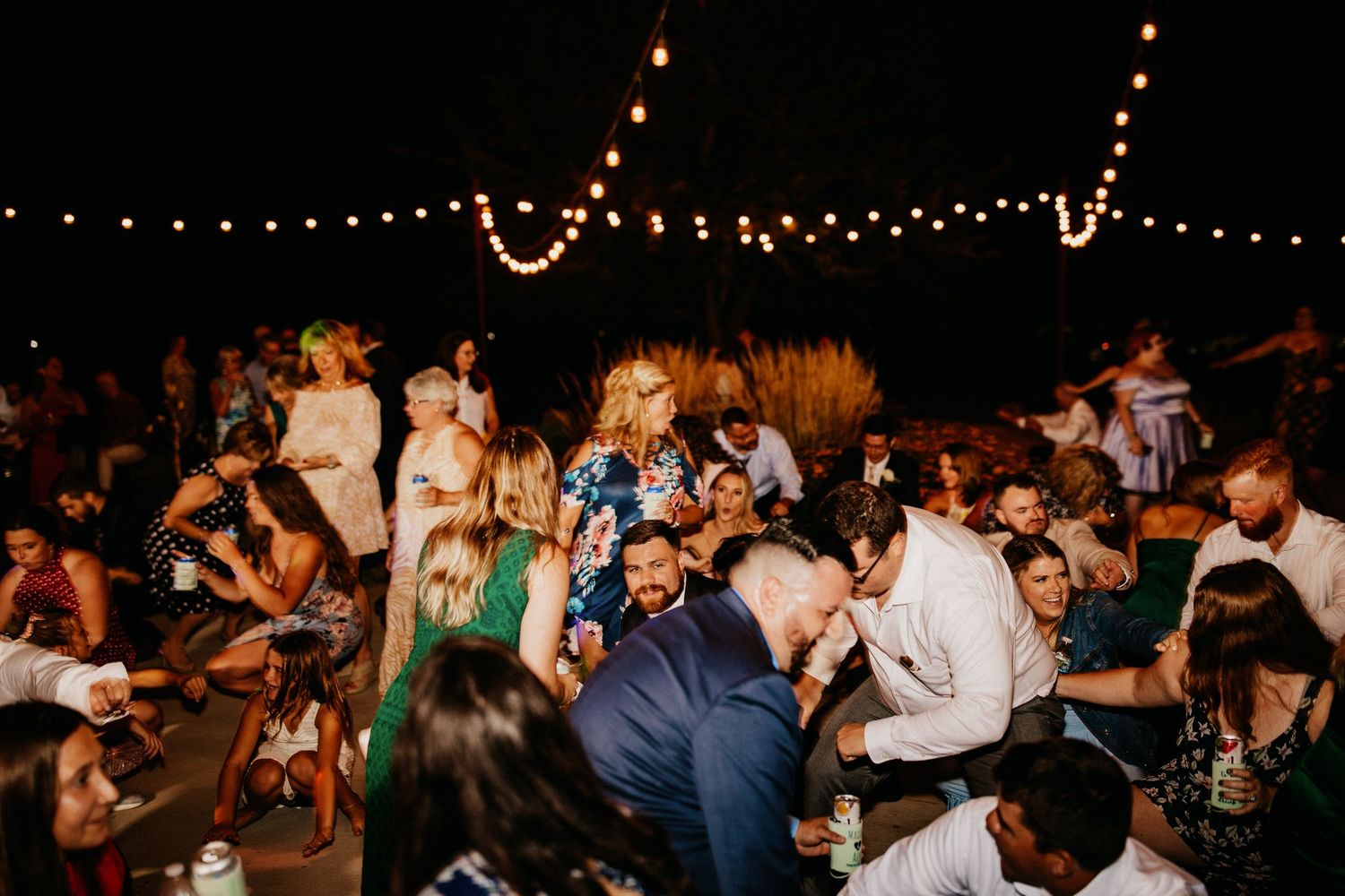Nighttime wedding reception with string lights and dancing guests.