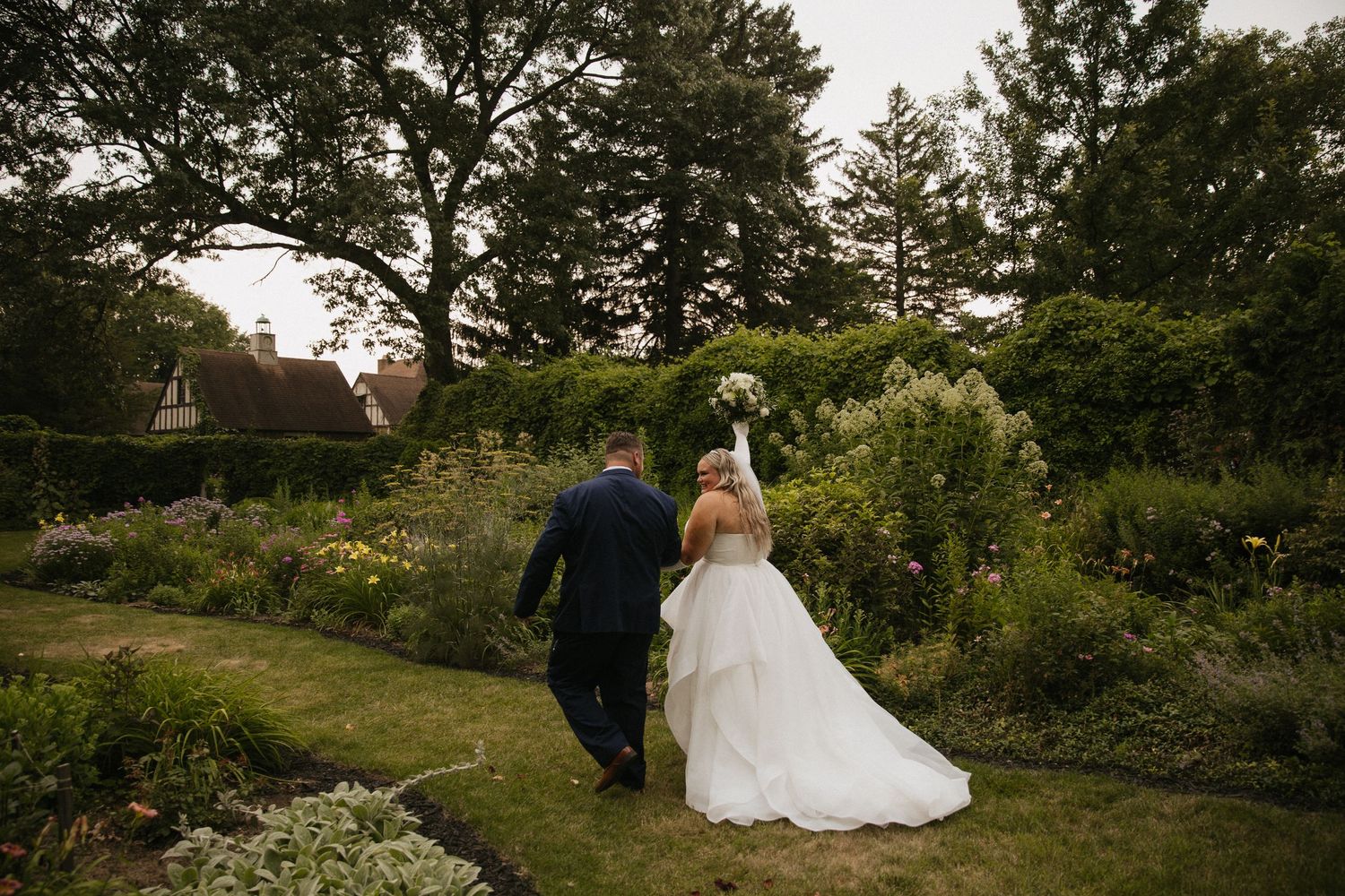 Outdoor wedding ceremony setup in a garden with tall pine trees in the background.