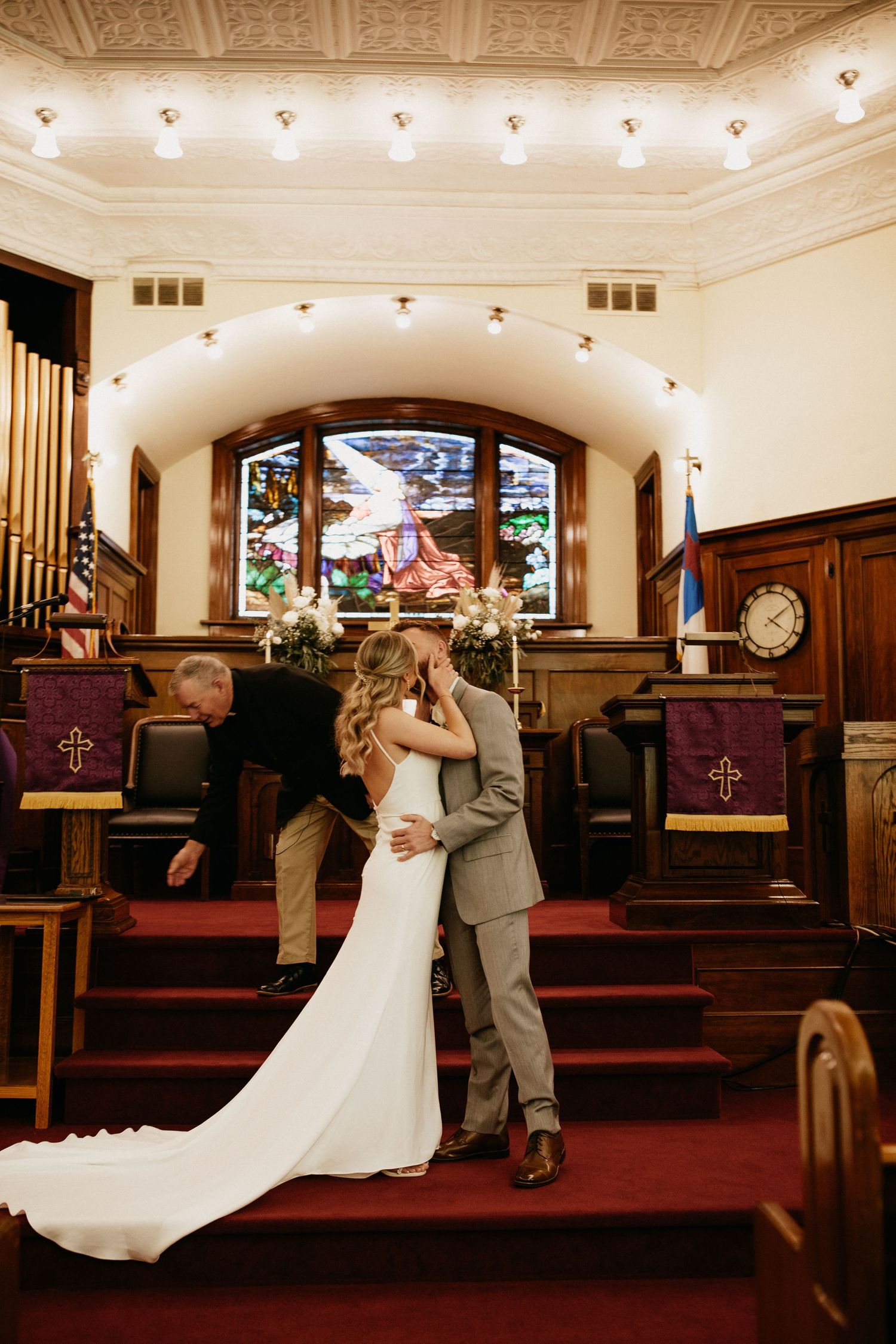 A romantic wedding ceremony moment in a church with ornate ceiling details and stained glass windows.