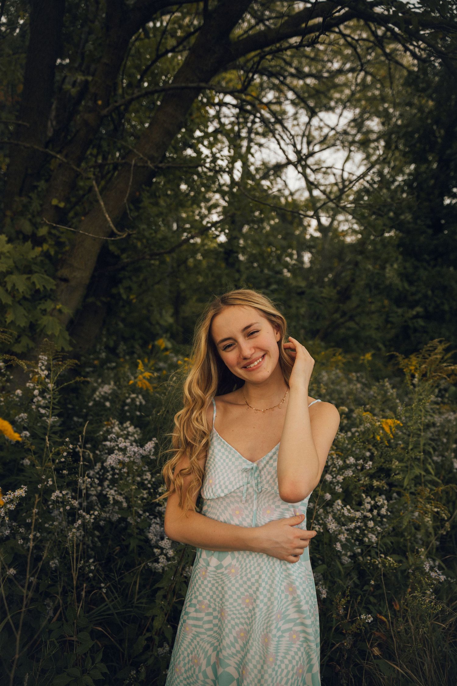 A candid summer portrait of a woman in a patterned dress surrounded by nature.